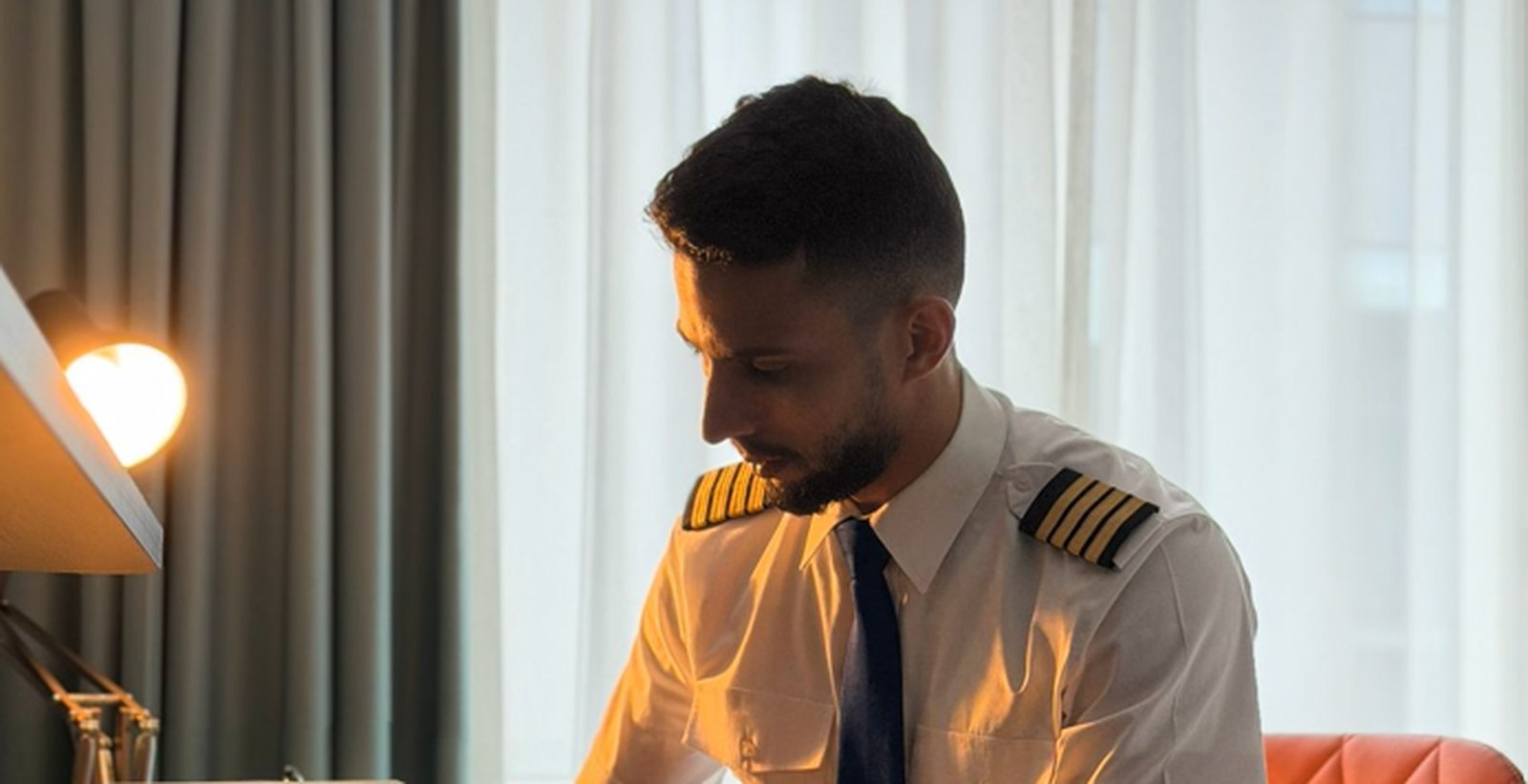 Capt. Yassine in uniform, sitting at a hotel desk with a book open in front of him